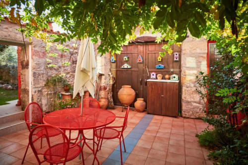 Pátio encantador da villa SOTAM Country House com móveis vermelhos, vasos de terracota e paredes de pedra cobertas de hera