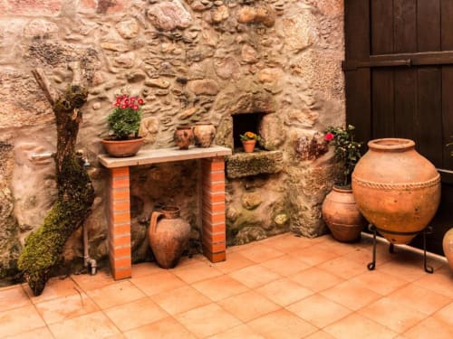 Pátio da villa portuguesa rústica com cerâmica em barro, flores em vasos, muros de pedra e arquitetura tradicional no SOTAM