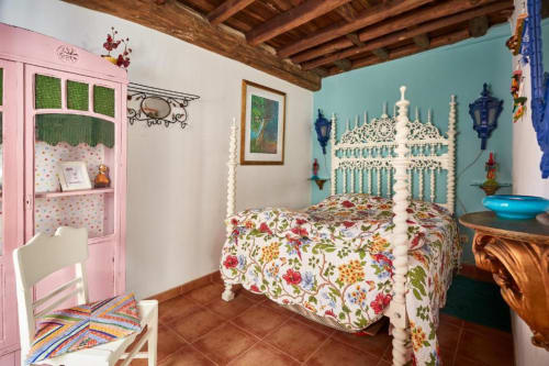 Quarto colorido na villa SOTAM Country House com cama floral, criado rosa, paredes turquesas e vigas de madeira