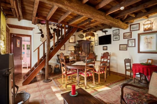 Sala de jantar rústica em quinta portuguesa com vigas de madeira à vista, cadeiras tradicionais e pavimento em terracota na SOTAM Country