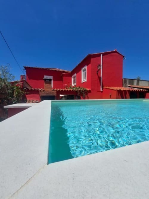 Villa vermelha vibrante com piscina turquesa e deck branco na SOTAM Country House, hospedagem boutique portuguesa