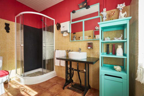 Banheiro colorido com azulejos amarelos, paredes vermelhas, prateleiras turquesas e decorações de gatos na villa SOTAM Country House