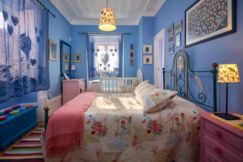 Quarto azul brilhante na villa SOTAM Country House com roupa de cama floral, acentos rosa e berço em acomodação portuguesa
