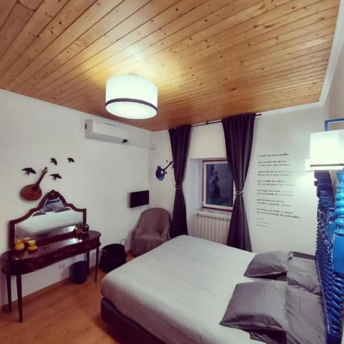 Suite moderna do SOTAM Country House em Góis com teto de madeira, janelas com vista para piscina, secretária e decoração de jardim