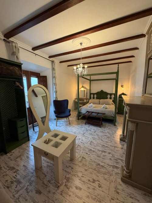 Elegante dormitorio en Complejo Turístico Retiro del Teatro con cama dosel verde, vigas vistas y mobiliario clásico