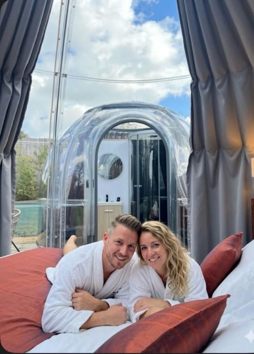 Couple se détendant dans la chambre bulle Topaze de l'hôtel Bubble Jade avec vue sur le jardin et jacuzzi privé