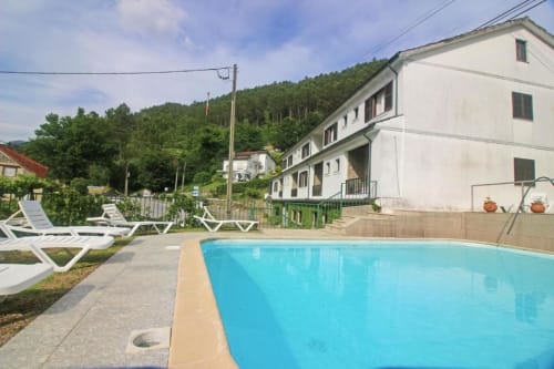 Serrana Gerês Inn swimming pool with loungers, white building, and green forested mountains in Gerês, Portugal