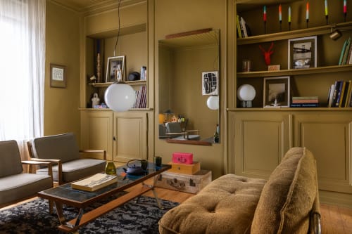 Salon chaleureux aux tons ocre du Moulin Moulin B&B à Dannes, avec mobilier vintage, étagères intégrées et décoration mi-siècle