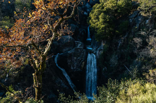 Cascata fluindo entre penhascos rochosos com vegetação verde ao redor da Pousada Serrana Gerês em Gerês, Portugal