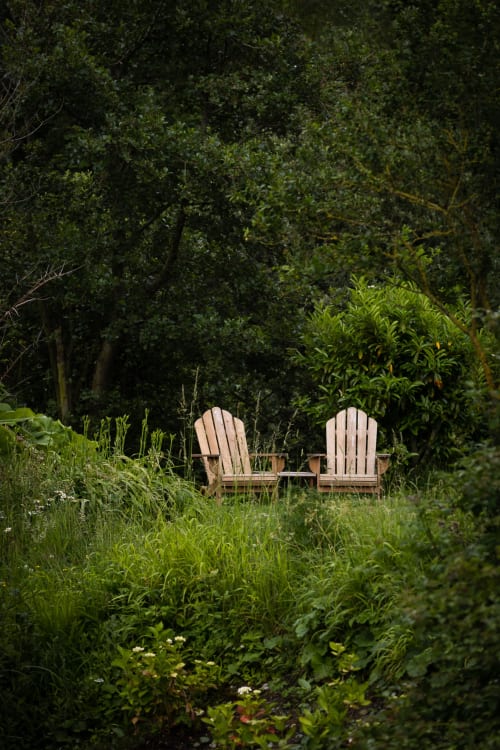 Deux chaises Adirondack en bois dans un jardin luxuriant du Moulin Moulin B&B à Dannes, France