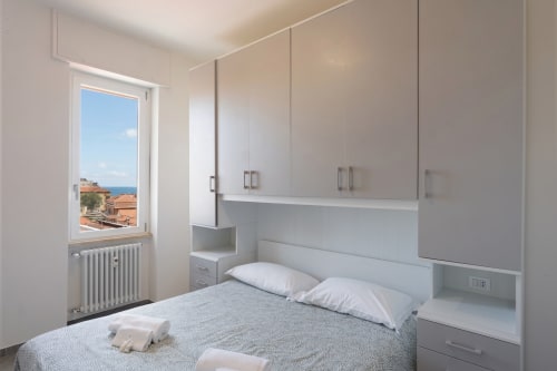 Camera moderna dell'appartamento Welcome Holiday Maestrale a Finale Ligure con vista sul mare, arredamento minimalista bianco e