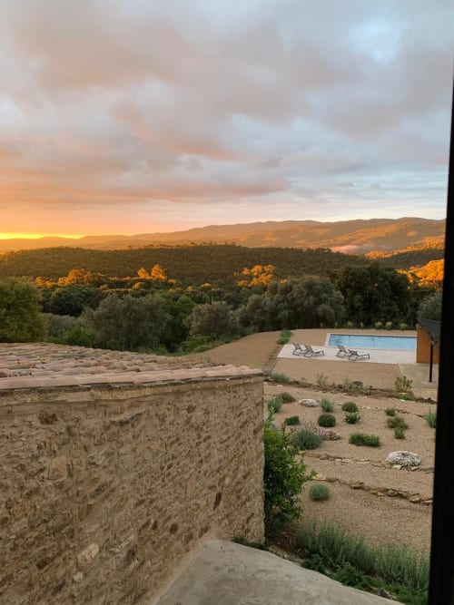 Vista del posta de sol de Mimosa Lodge sobre el bosc de Montnegre amb piscina i propietat de pedra en terrasses a la vesprada