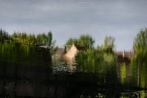 Vue floutée au bord de l'eau avec saules et structures en brique à Moulin Moulin B&B à Dannes, France