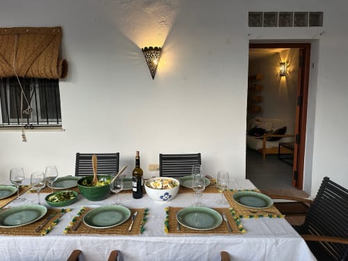 Table de dîner en plein air dressée à Slowvejer à Véjer de la Frontera avec assiettes vertes, vin et amuse-bouches