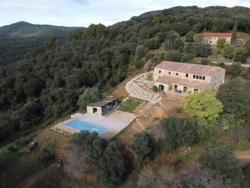 Vista aèria de l'allotjament Mimosa anidat en el bosc de Montnegre amb edificis de pedra, piscina i voltants