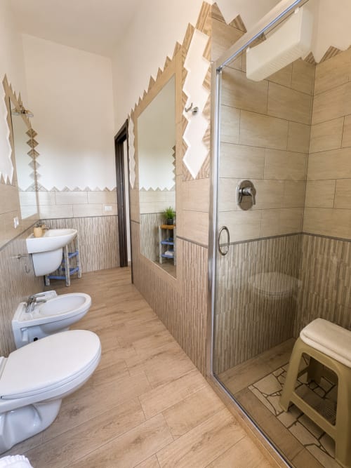 Modernes Badezimmer mit begehbarer Dusche, Doppelwaschbecken und Holzoptik-Fliesen im Molti Mari B&B, Sardinien