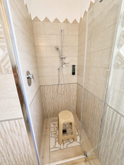 Modernes Duschbad mit beigen Fliesen und hölzernem Trittschemel im Molti Mari B&B in Olbia, Italien