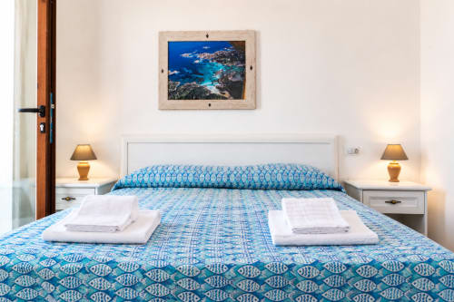 Küstenzimmer im Molti Mari B&B mit blauem Musterbettzeug, Meereskunst und Doppelnachttischlampen