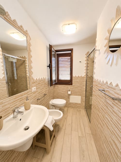 Modernes Badezimmer im Molti Mari B&B in Murta Maria mit Doppelwaschbecken, bodengleicher Dusche und holzstrukturiertem Fliesenbelag
