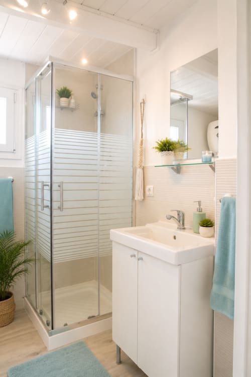 Modernes Badezimmer mit Glasdusche, weißem Waschbecken, Spiegel und türkisfarbenen Handtüchern im Sara & Gino Fuerteventura