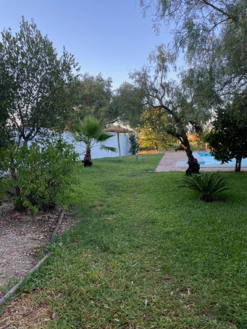Jardin luxuriant de l'hôtel Slowvejer à Vejer de la Frontera avec piscine, arbres matures et vue sur l'eau