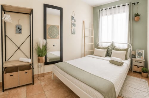Modernes Schlafzimmer im Apartment Sara & Gino in Corralejo mit weißem Metallbett, grünen Akzenten, Möbeln aus Holz und Spiegel