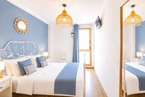 Modernes Schlafzimmer im Sara & Gino Fuerteventura mit blauer Akzentwand, geflochtenen Pendelleuchten und Meerblick in Corralejo