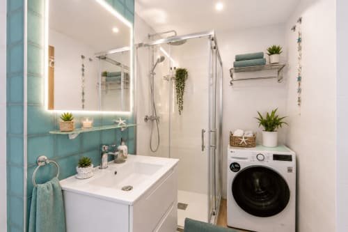 Modernes Badezimmer im Apartment Sara & Gino Fuerteventura mit türkisfarbenen Fliesen, beleuchtetem Spiegel, weißem Waschbecken, Dusche und Waschmaschine