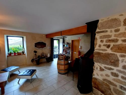 Intérieur en pierre brute aux Gîtes Du Couvent en Ardèche avec poutres en bois, décor de tonneau et espace commun accueillant