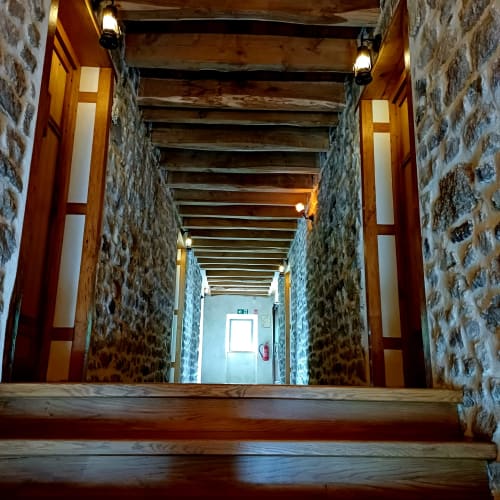 Couloir en pierre aux poutres en bois des Gîtes Du Couvent, charmante maison d'hôtes à Nozières, Ardèche