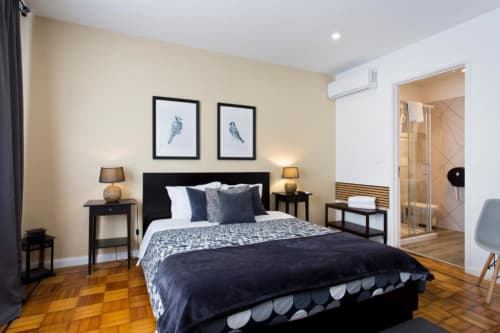 Modern family room at Cem Contos Porto with queen bed, black headboard, hardwood floors, and ensuite bathroom access