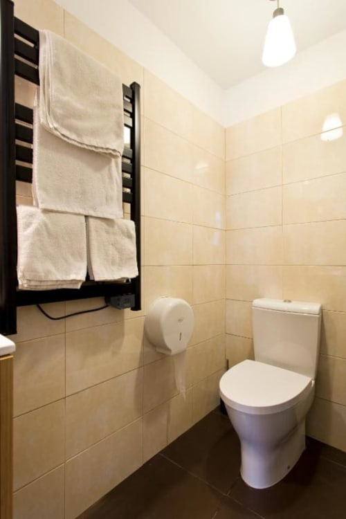 Modern bathroom at Cem Contos Porto with heated towel rack, white toilet, beige tile walls, and pendant lighting