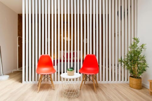 Modern seating area at Cem Contos Porto with red chairs, white accent table, and bamboo plant