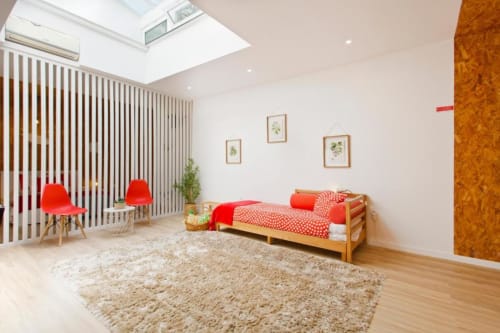 Bright Family Studio at Cem Contos Porto with wooden bed, red bedding, beige rug, modern red chairs, and skylight.