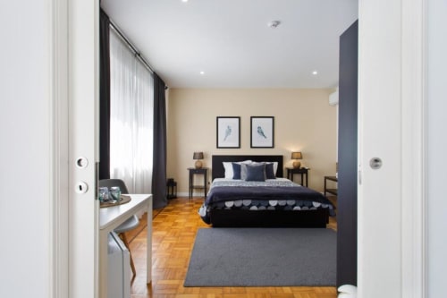 Chambre moderne au Cem Contos Porto avec lit noir, murs beige, parquets et mobilier contemporain