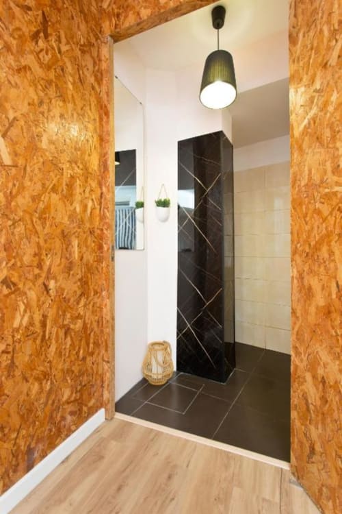 Modern bathroom at Cem Contos Porto with cork walls, black tiled shower enclosure, and green pendant light fixture