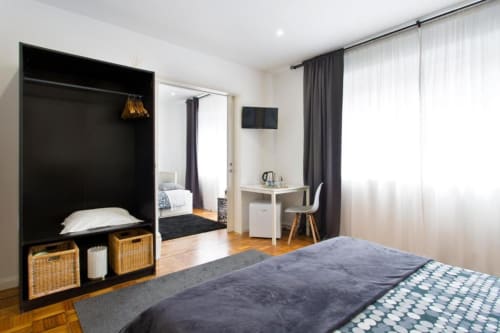 Family room at Cem Contos B&B Porto with black canopy bed, workspace desk, and modern furnishings on hardwood floors