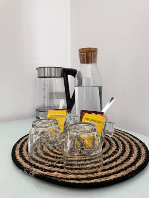 Tea and coffee service set with glasses, electric kettle, and water bottle on decorative coaster in Cem Contos family room,