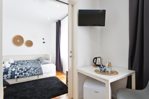 Family Room at Cem Contos Porto featuring bed with patterned bedding, wall-mounted TV, desk with electric kettle, and