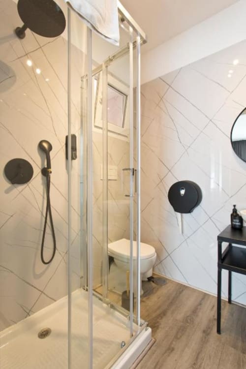 Modern bathroom in Cem Contos Porto family room with walk-in shower, toilet, black fixtures, and diagonal tile walls