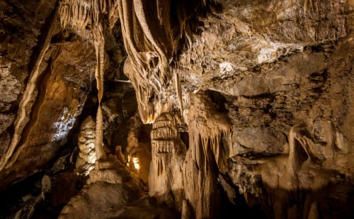 Magnifiques formations souterraines avec stalactites et stalagmites illuminées de teintes chaudes au Domaine de Cabrières, St Jean Du Gard