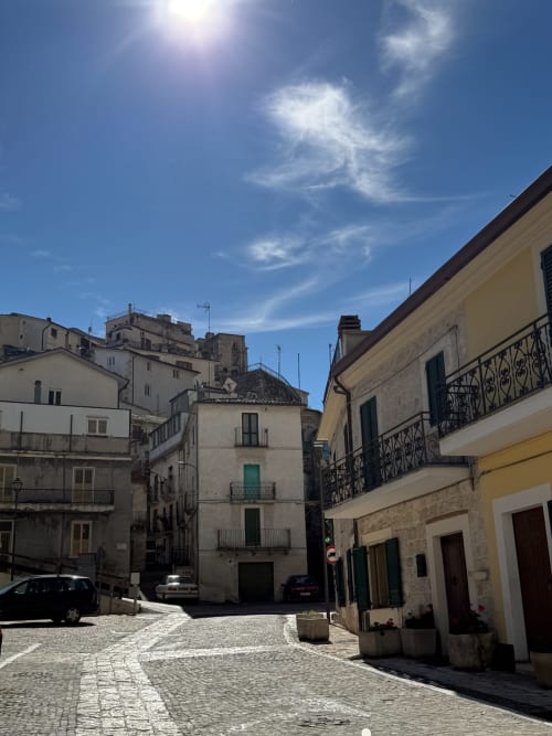 Piazza soleggiata ad Atessa con edifici storici in pietra e strada acciottolata presso Tales of Abruzzo