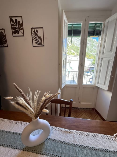 Moderna sala da pranzo nell'appartamento Tales of Abruzzo con decorazioni di pampas grass, tavolo in legno e porte del balcone aperte sulla vista