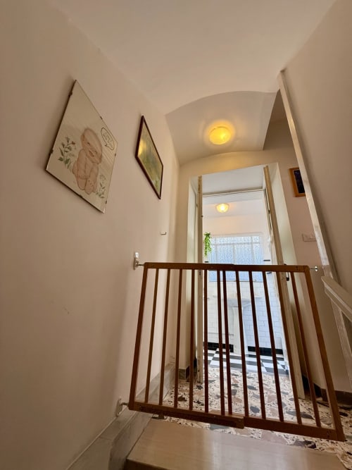 Luminoso corridoio con cancellata in legno dell'appartamento Tales of Abruzzo ad Atessa, Italia, con opere botaniche incorniciate