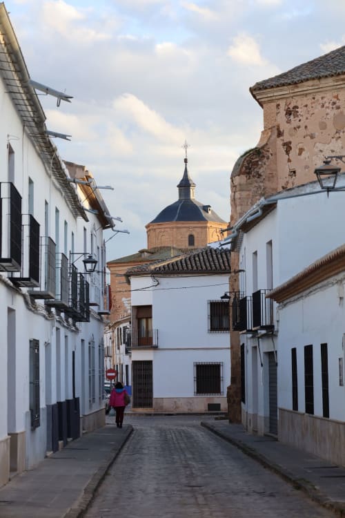 Historic cobblestone street in Almagro with white-washed buildings and church dome, Complejo Turístico Retiro del Teatro
