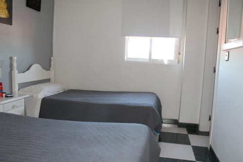 Habitación doble en Hostal El Camionero de Burguillos del Cerro con dos camas, muebles blancos y ventana luminosa