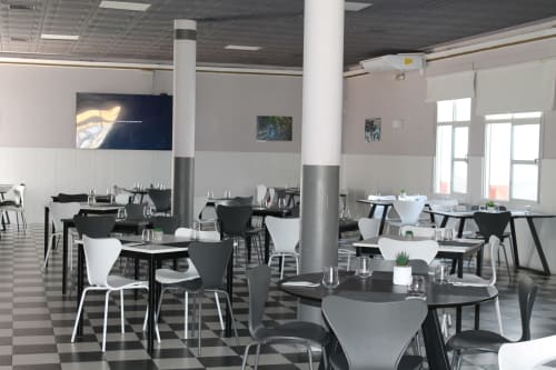 Comedor moderno del Hostal El Camionero con sillas y mesas en blanco y negro, amplios ventanales con vistas a Burguillos