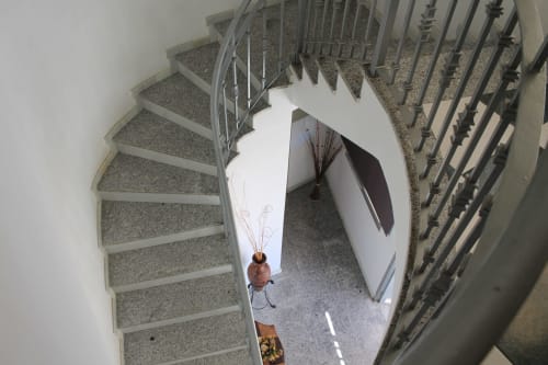 Vista cenital de escalera de caracol en Hostal El Camionero de Burguillos del Cerro con huésped subiendo con equipaje