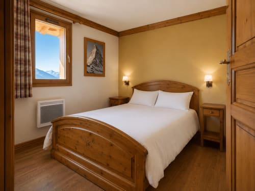 Chambre douillette en bois au Chalet des Cimes avec vue montagne, literie blanche et décor alpin à Belle Plagne