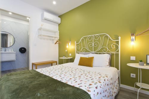 Chambre moderne de la maison d'hôtes Cem Contos B&B Porto avec murs vert olive, lit en métal ouvragé et salle de bain privée